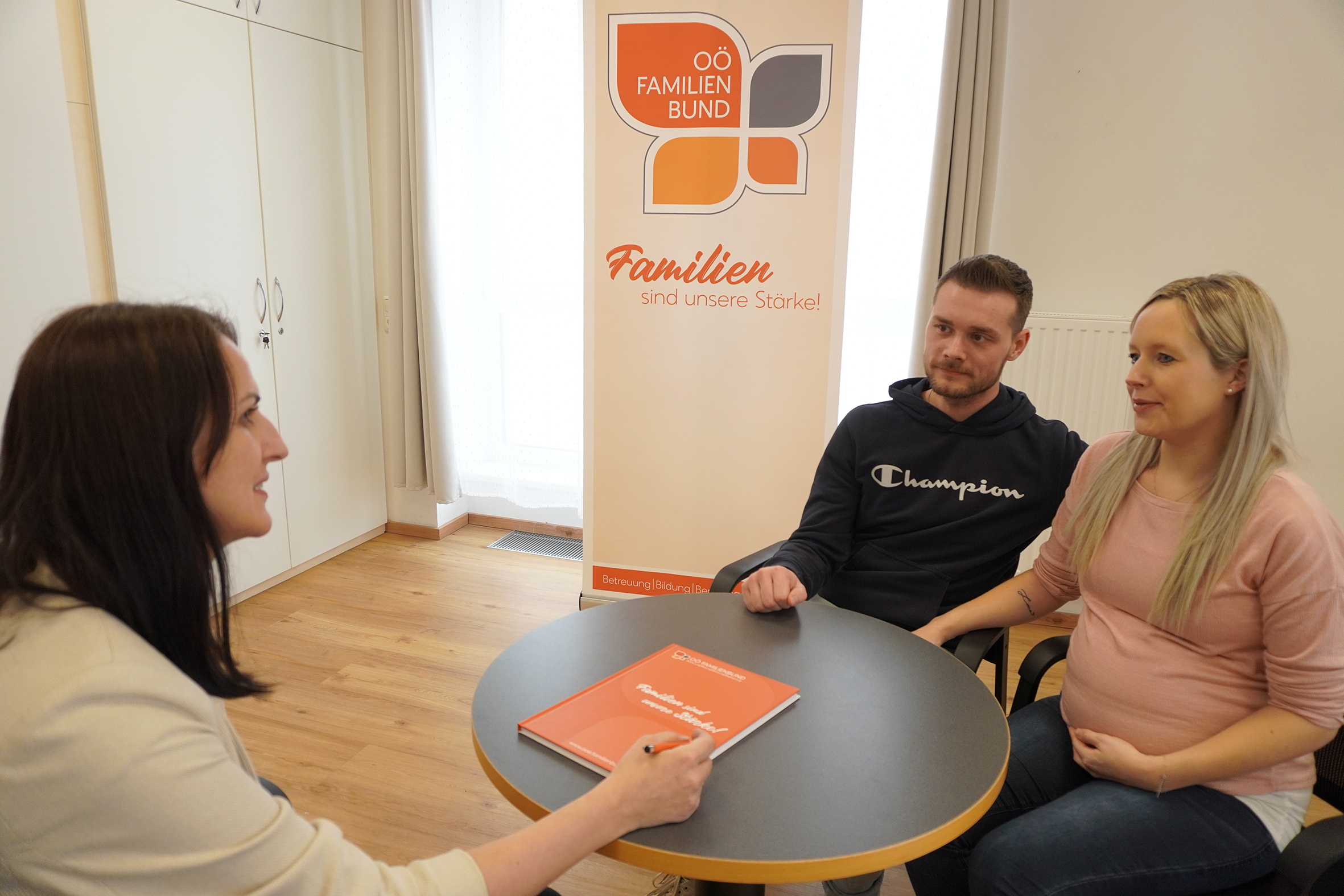 Eltern-Kind-Pass, Elternberatung, Eltern sitzen mit Beraterin am Tisch