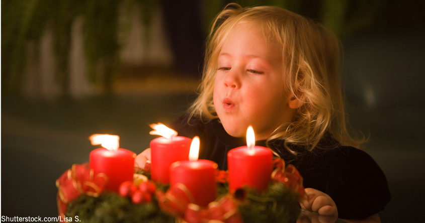 Mädchen bläste Kerze am Adventkranz aus