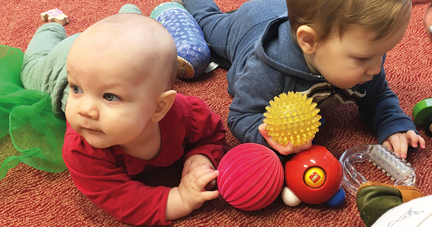 2 Babys am Boden liegend und Bälle