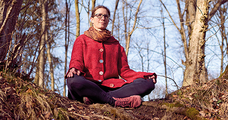 Frau im Yogasitz im Wald