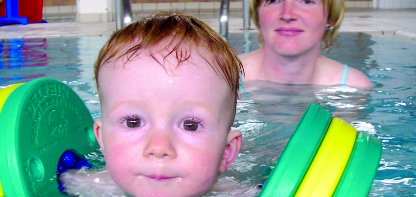 Baby im Wasser mit Schwimmscheiben