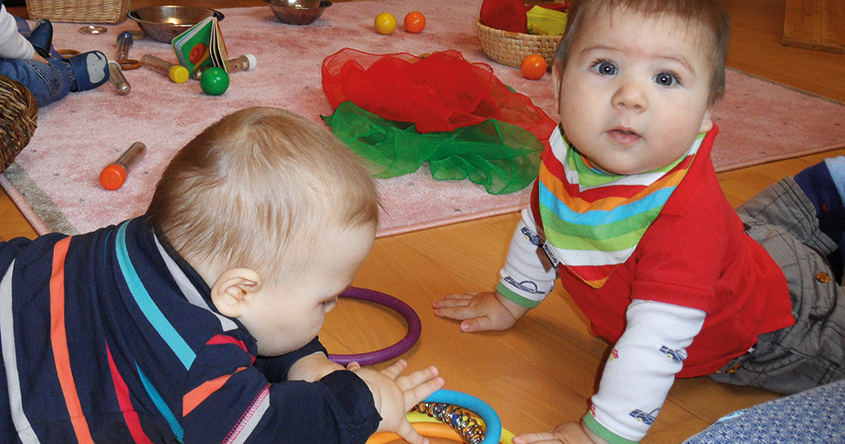 2 Babys am Bauch mit aufgestützten Armen liegen sich gegenüber