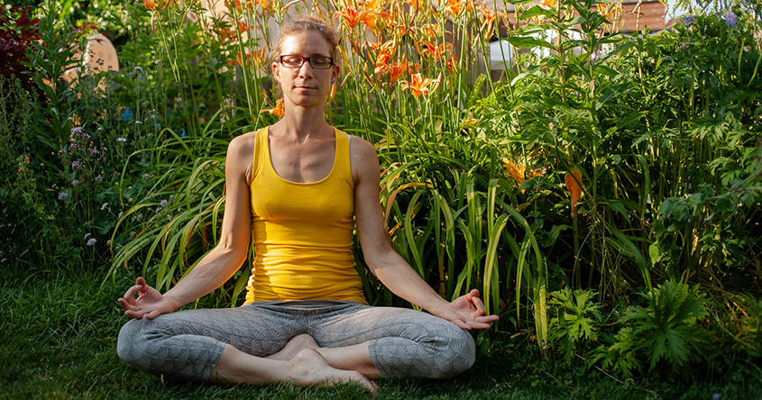 Frau im  Yogasitz im Garten